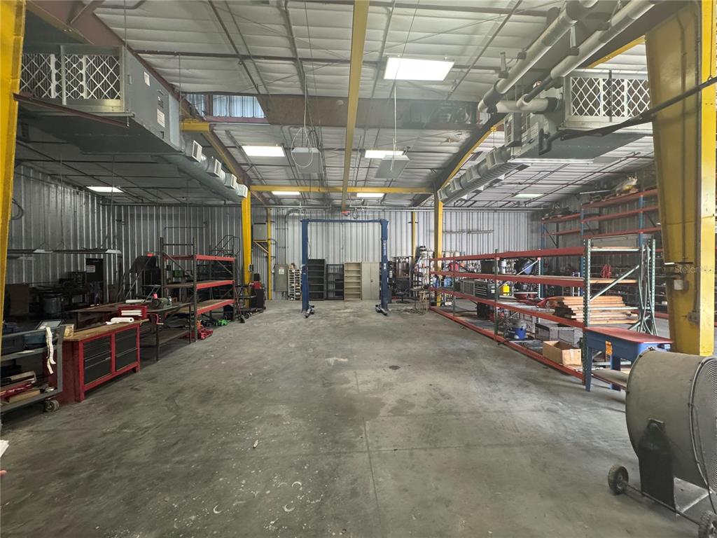 A large industrial warehouse space features concrete floors, metal walls, and tall storage shelving units — 2251 TOPLINE WAY UNIT 2, BROOKSVILLE, FL
