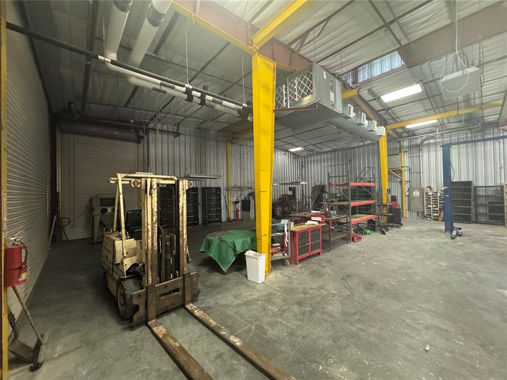 A warehouse interior features a forklift, metal shelving, a workbench, and exposed ceiling ductwork — 2251 TOPLINE WAY UNIT 2, BROOKSVILLE, FL