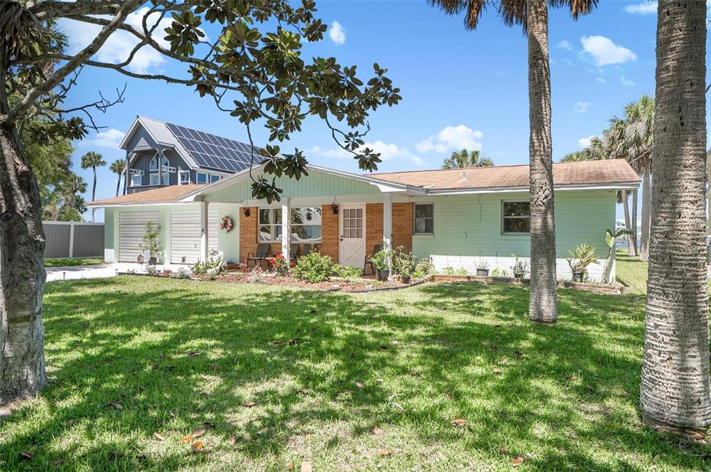 A single-story house with light green siding, a covered porch, and a large front lawn — 420 LAMBERT AVENUE, FLAGLER BEACH, FL
