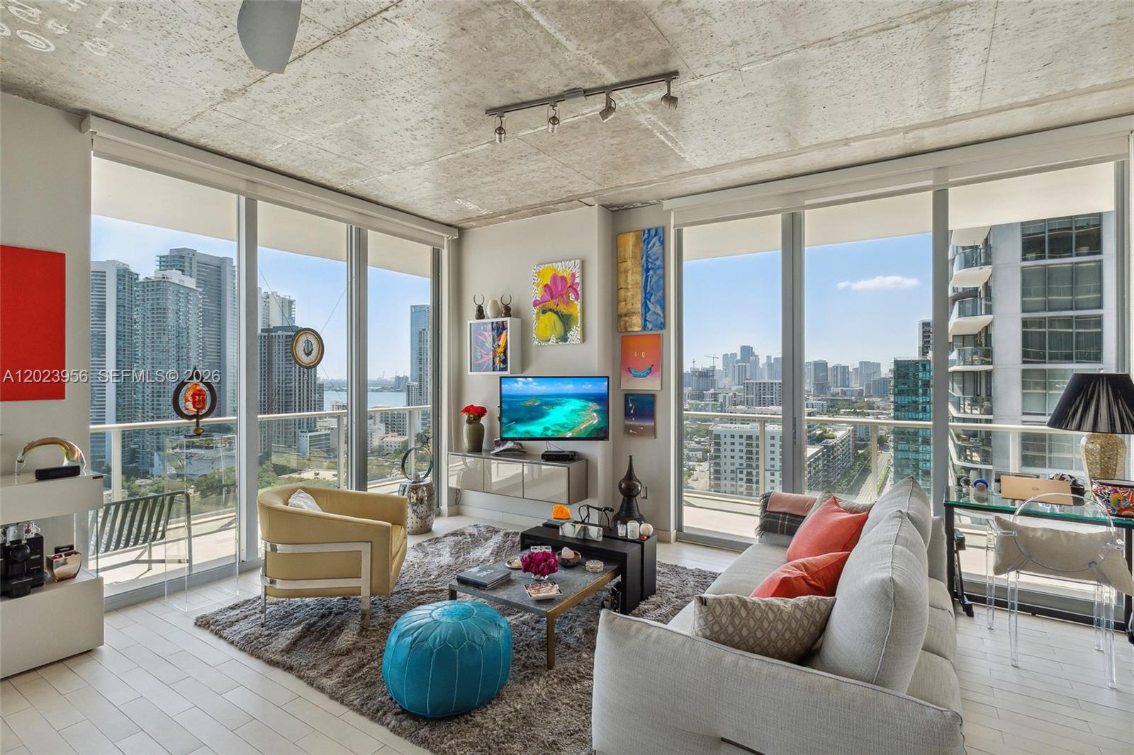 A modern living room features floor-to-ceiling windows, a concrete ceiling, and a city skyline view — 3470 E Coast Ave # H2309, Miami FL 33137, MIAMI, FL
