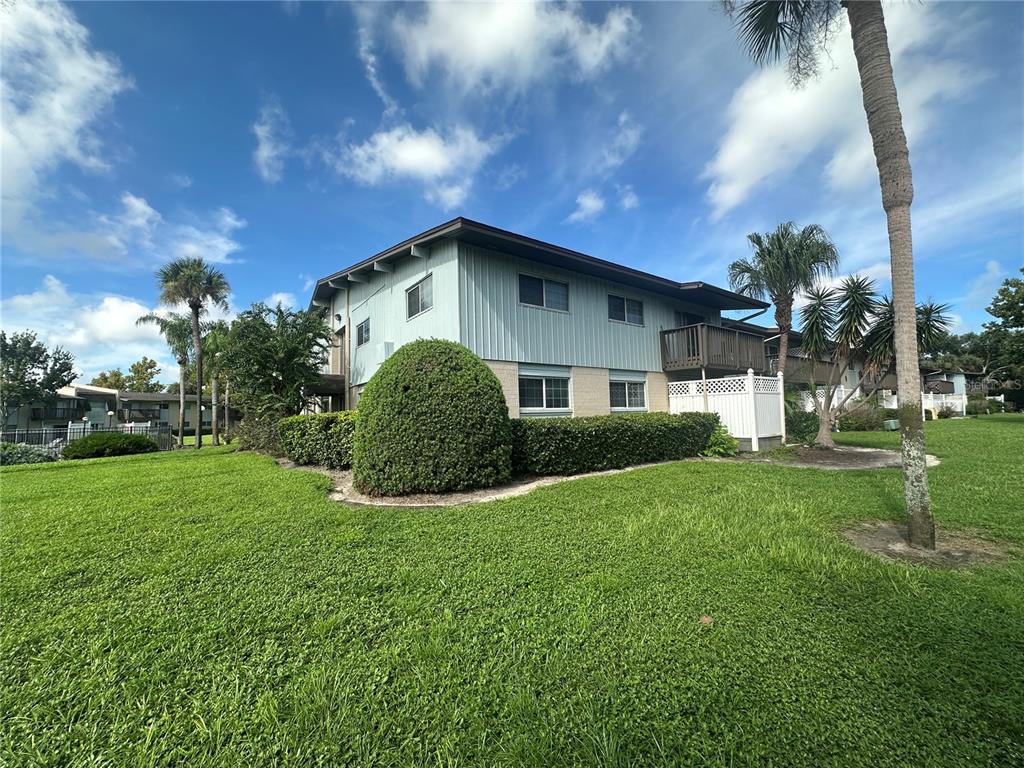 A two-story apartment building with light blue siding, a brick base, and manicured landscaping — 1695 LEE ROAD UNIT E116, WINTER PARK, FL