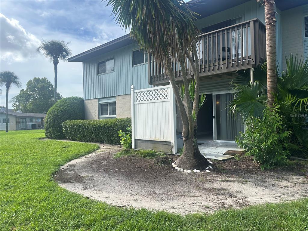 A two-story apartment building exterior features a ground-level patio, a second-story balcony, and palm trees — 1695 LEE ROAD UNIT E116, WINTER PARK, FL