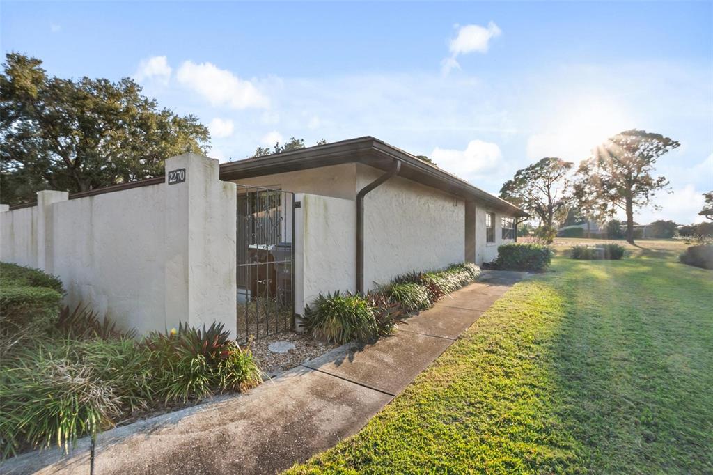 A single-story house exterior features a stucco wall, a metal gate, and a concrete walkway — 2270 FIRESTONE PLACE, WINTER HAVEN, FL