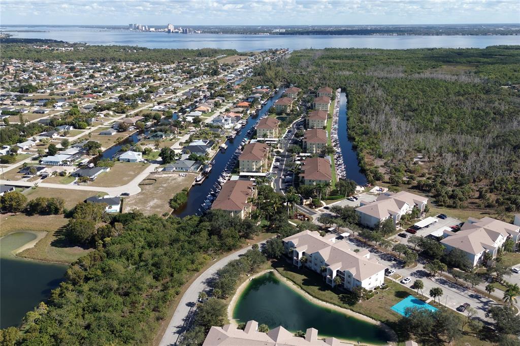An aerial view shows a residential complex with a canal, boat slips, and nearby water — 1771 FOUR MILE COVE PARKWAY UNIT 1031, CAPE CORAL, FL