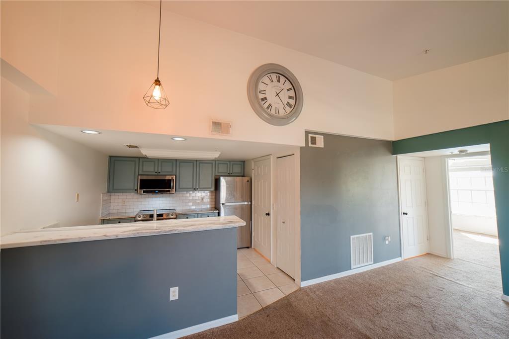 A kitchen with blue cabinets and a breakfast bar overlooks a carpeted living area — 1771 FOUR MILE COVE PARKWAY UNIT 1031, CAPE CORAL, FL
