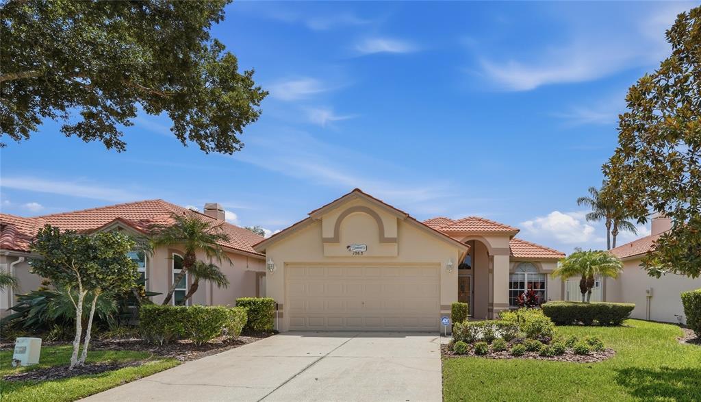 A single-story house with a beige stucco exterior, a tile roof, and a two-car garage — 1063 DARTFORD DRIVE, TARPON SPRINGS, FL