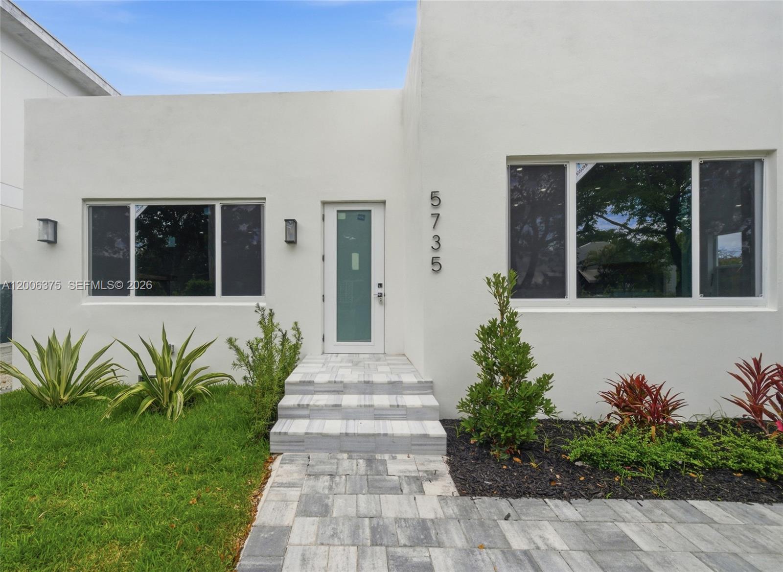 The exterior of a white modern house features a glass-paneled front door and stone steps — 5735 SW 12th St, West Miami FL 33144, WEST MIAMI, FL