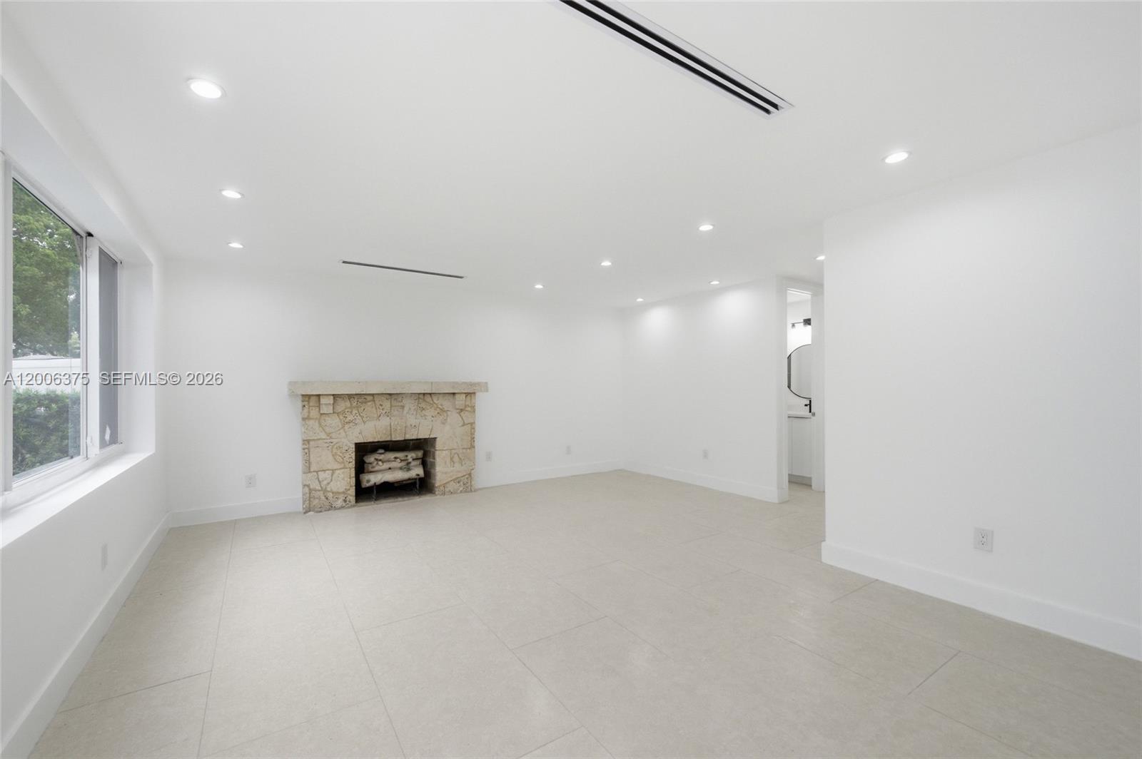 A minimalist living room features white walls, large floor tiles, and a stone fireplace — 5735 SW 12th St, West Miami FL 33144, WEST MIAMI, FL