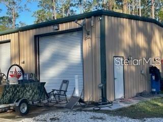 A metal workshop building with a roll-up garage door and a side entry door — 1501 PEARL STREET, LONGWOOD, FL