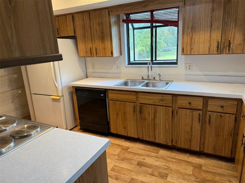 A kitchen features wood-grain cabinets, a white refrigerator, a black dishwasher, and a double sink — 9720 SW 130TH AVENUE, DUNNELLON, FL