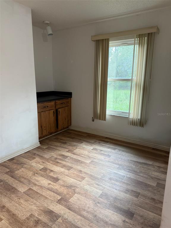 A room with wood-look flooring, a window with vertical blinds, and a small wooden cabinet — 9720 SW 130TH AVENUE, DUNNELLON, FL