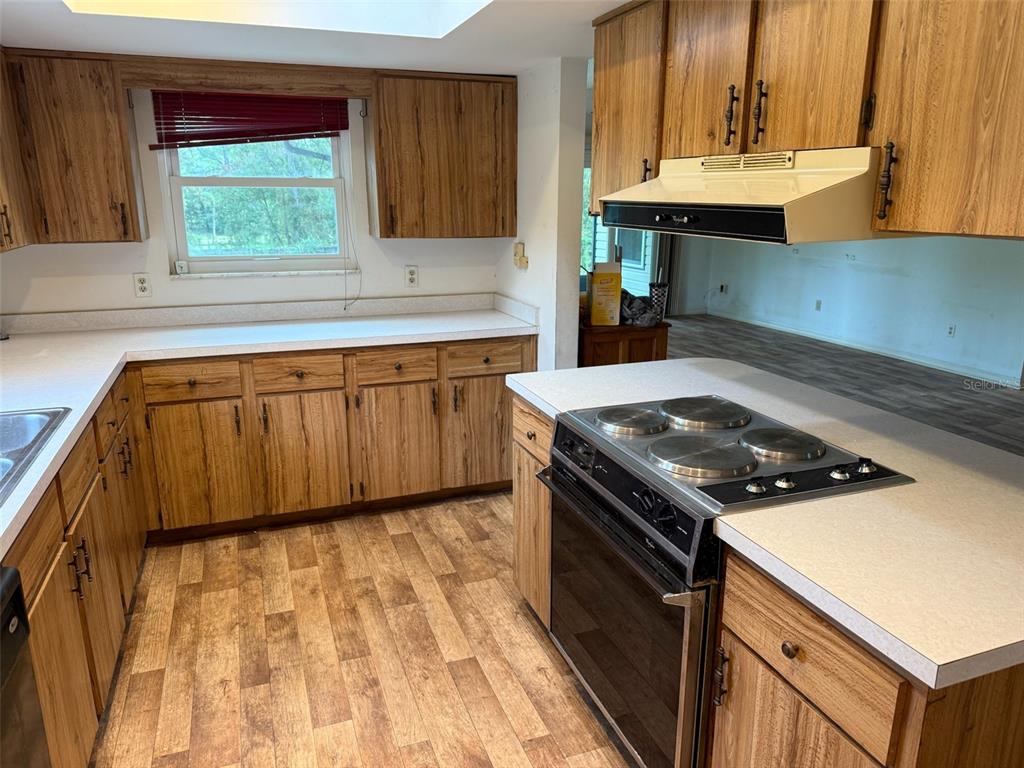 A kitchen features wood cabinets, white countertops, a drop-in stove, and wood-look flooring — 9720 SW 130TH AVENUE, DUNNELLON, FL