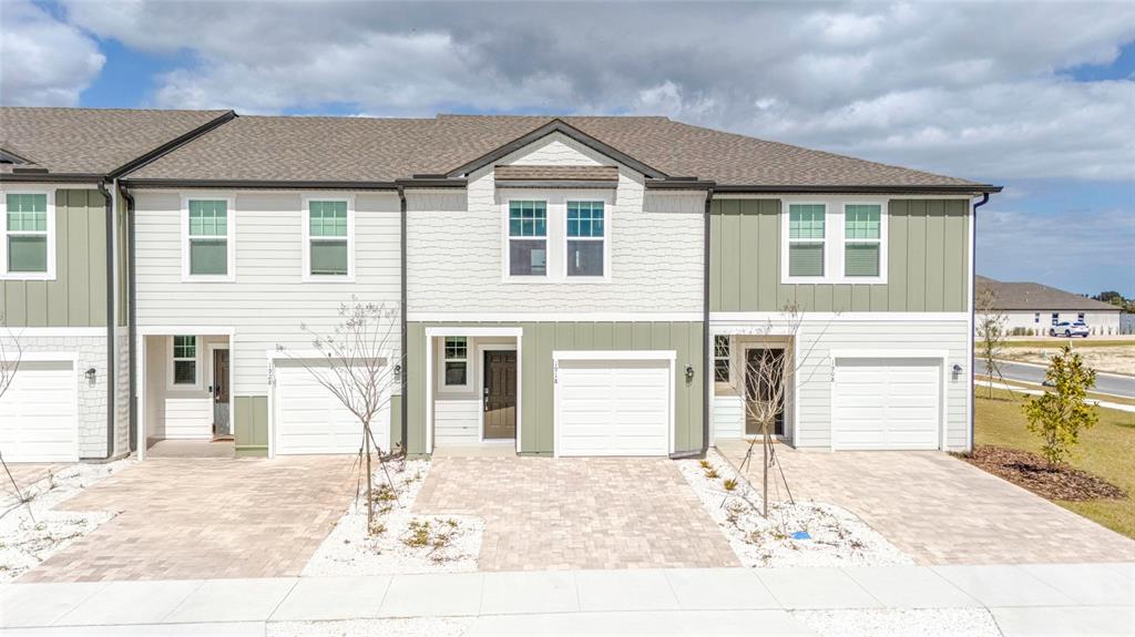 A row of three modern townhomes features light-colored siding, attached garages, and paved driveways — 1918 BLUEWATER, ROCKLEDGE, FL