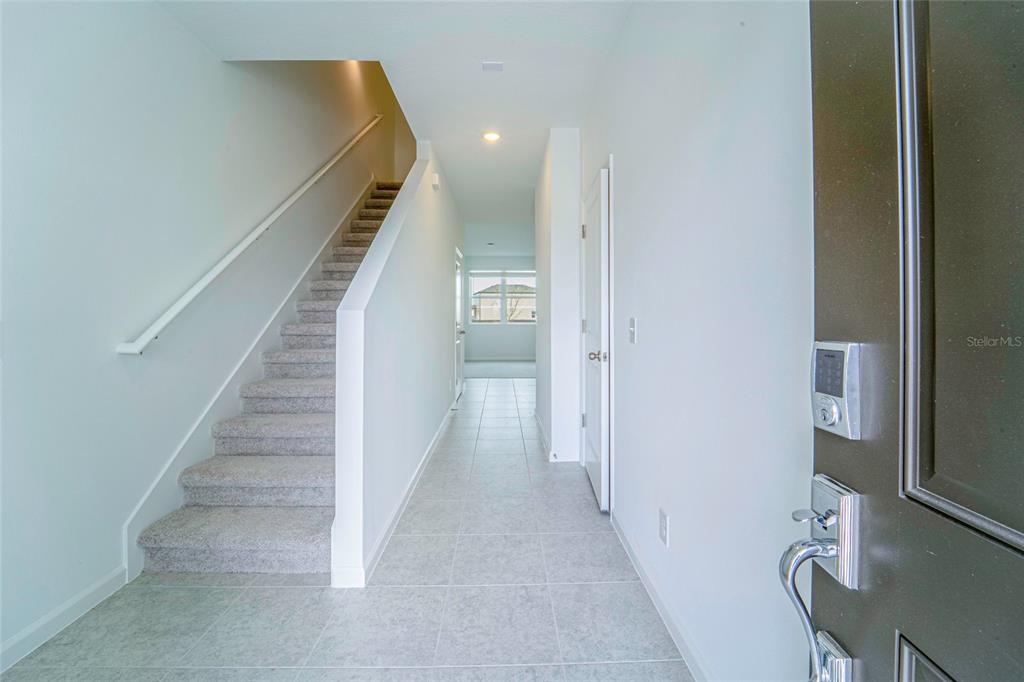 An entryway features a carpeted staircase, tiled flooring, and a dark front door — 1918 BLUEWATER, ROCKLEDGE, FL