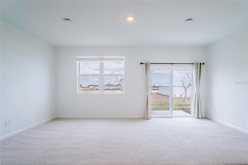 An empty room with beige carpet, white walls, a window, and sliding glass doors — 1918 BLUEWATER, ROCKLEDGE, FL