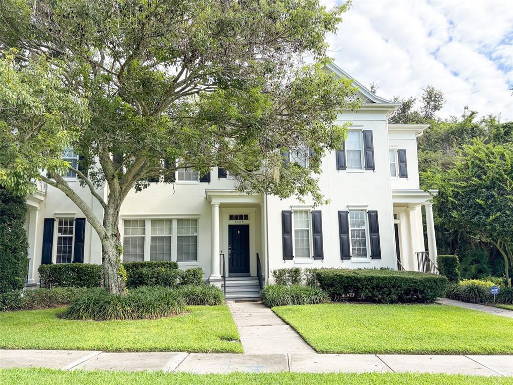 A two-story white house with black shutters and a large tree in the front yard — 5489 BALDWIN PARK STREET, ORLANDO, FL