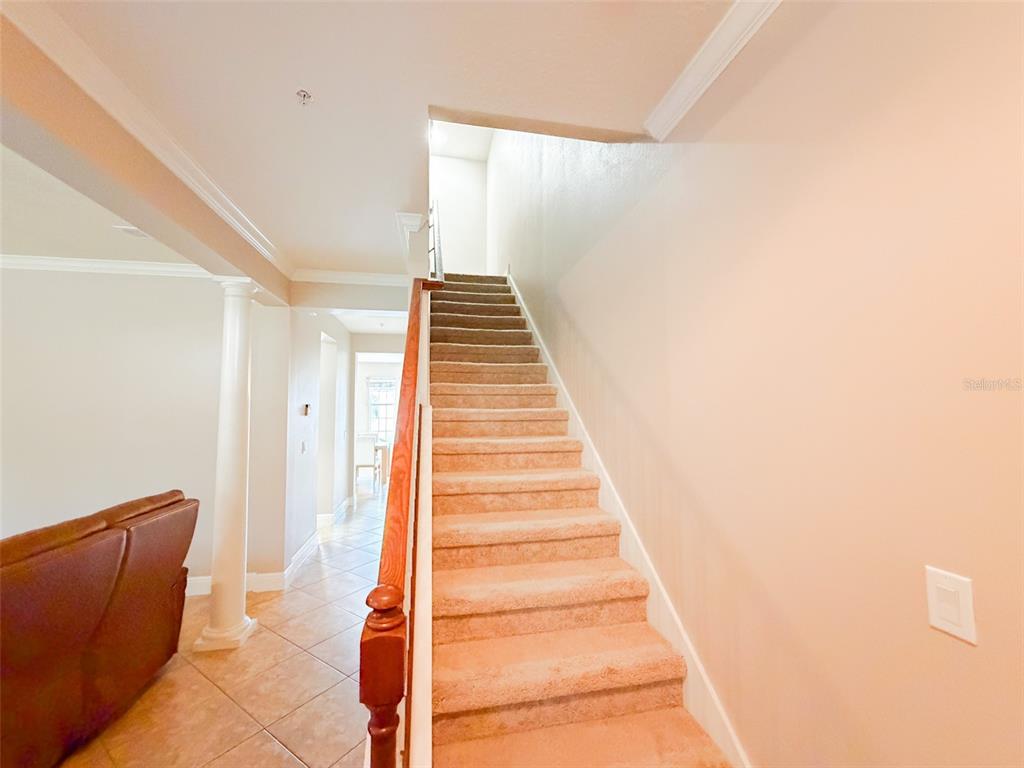 A carpeted staircase with a wooden railing leads to an upper level in a home — 5489 BALDWIN PARK STREET, ORLANDO, FL