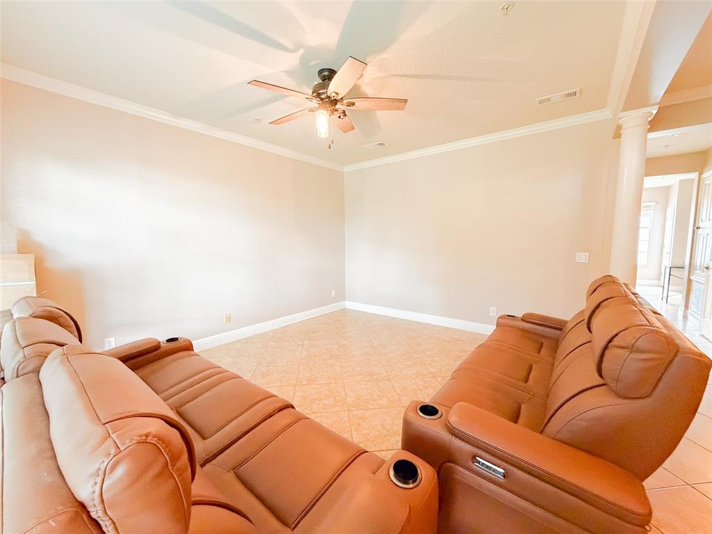 A living room features tan leather reclining sofas, tile flooring, and a ceiling fan — 5489 BALDWIN PARK STREET, ORLANDO, FL