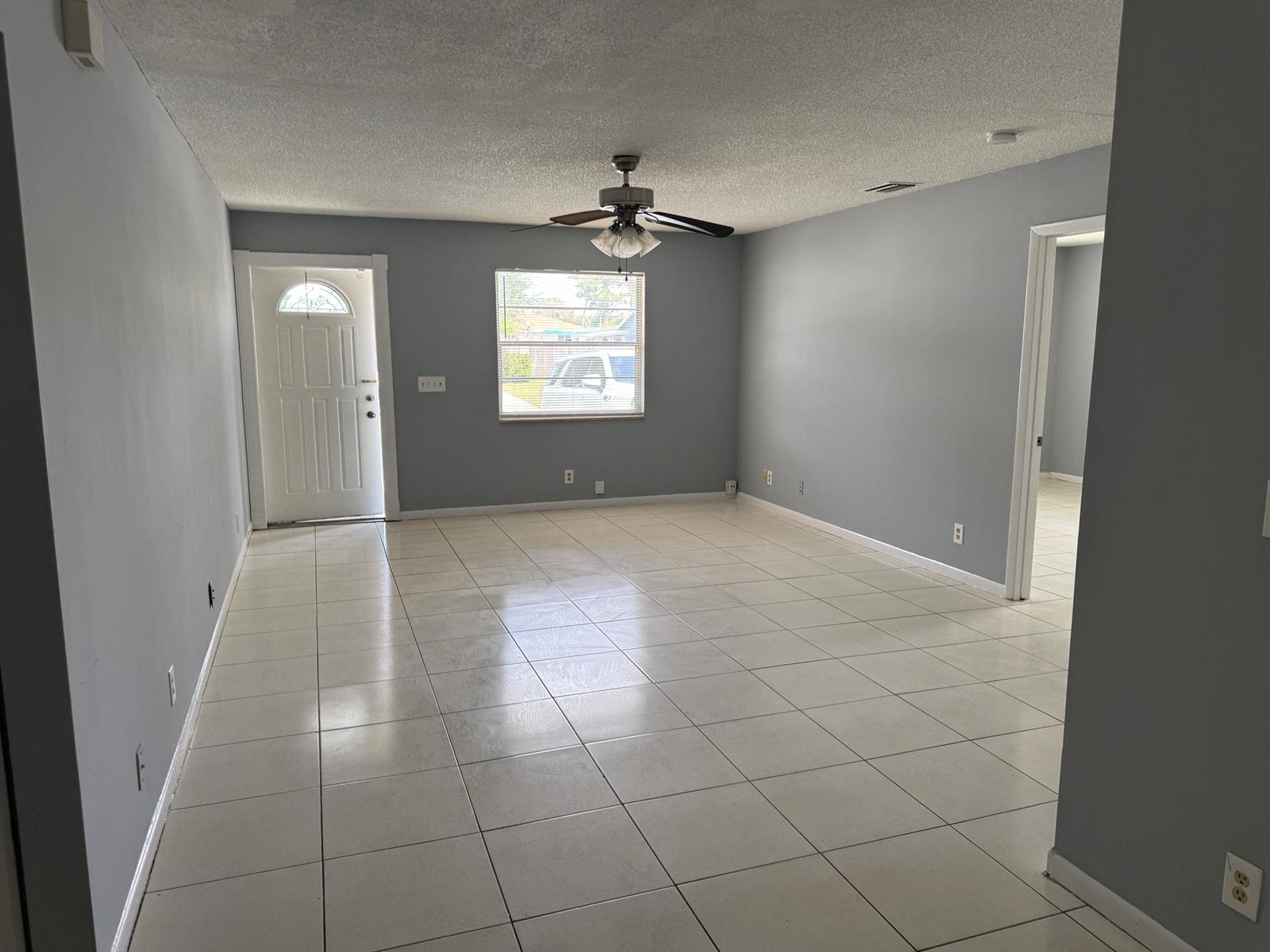An empty living room features light gray walls, white tile flooring, and a ceiling fan — 2519 Griffin Square, FL 33406, FL