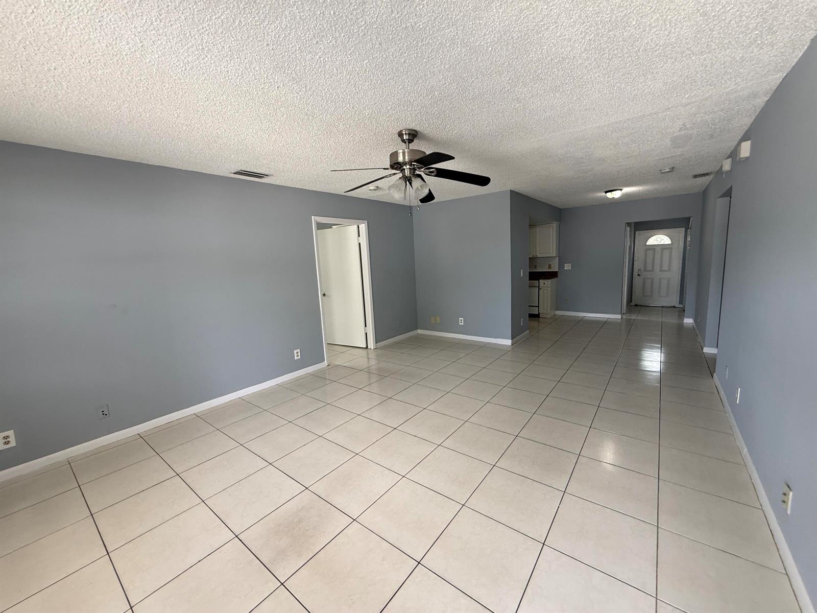 An empty living room with gray walls, white tile flooring, and a ceiling fan — 2519 Griffin Square, FL 33406, FL