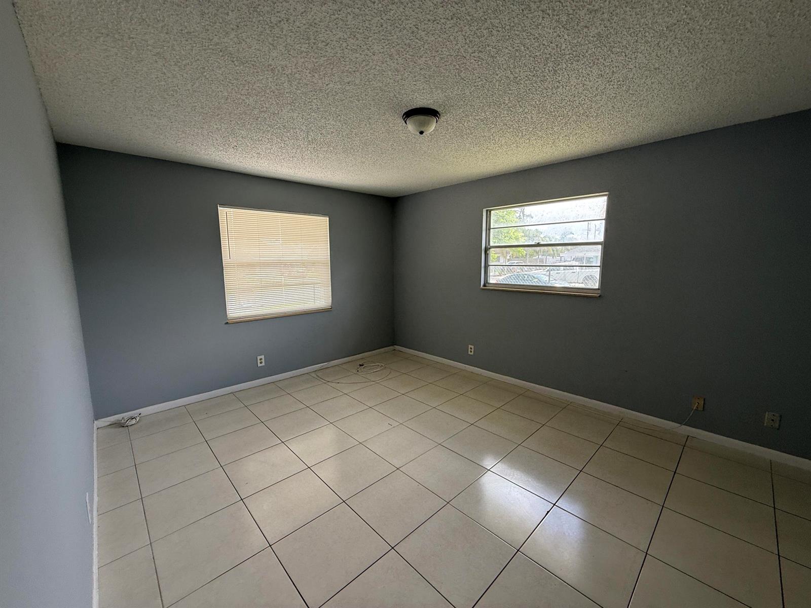 An empty room features gray walls, white tile flooring, and two windows with blinds — 2519 Griffin Square, FL 33406, FL