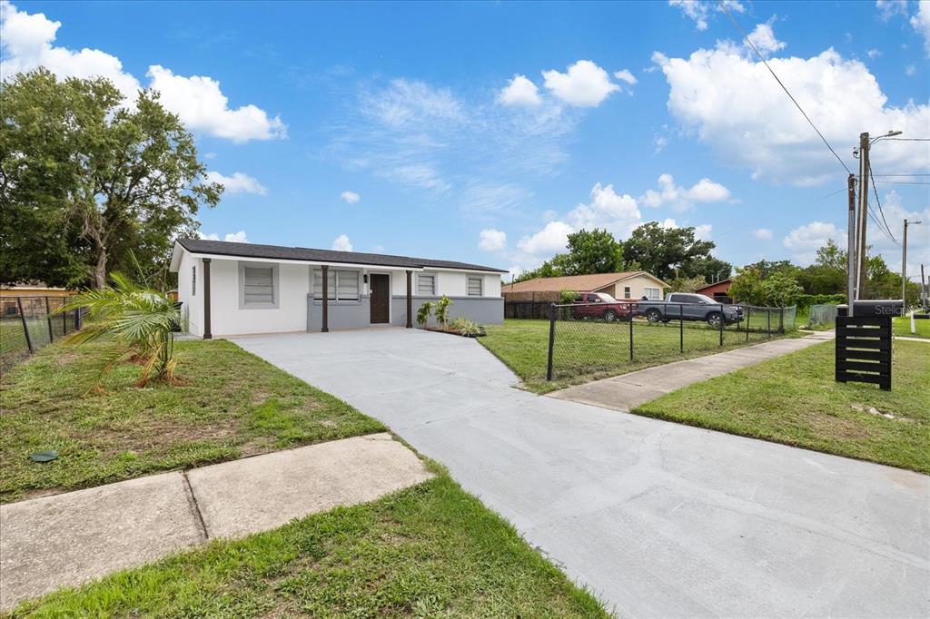 A single-story house with a white and gray exterior, a concrete driveway, and a chain-link fence — 8303 BAHIA AVENUE, TAMPA, FL