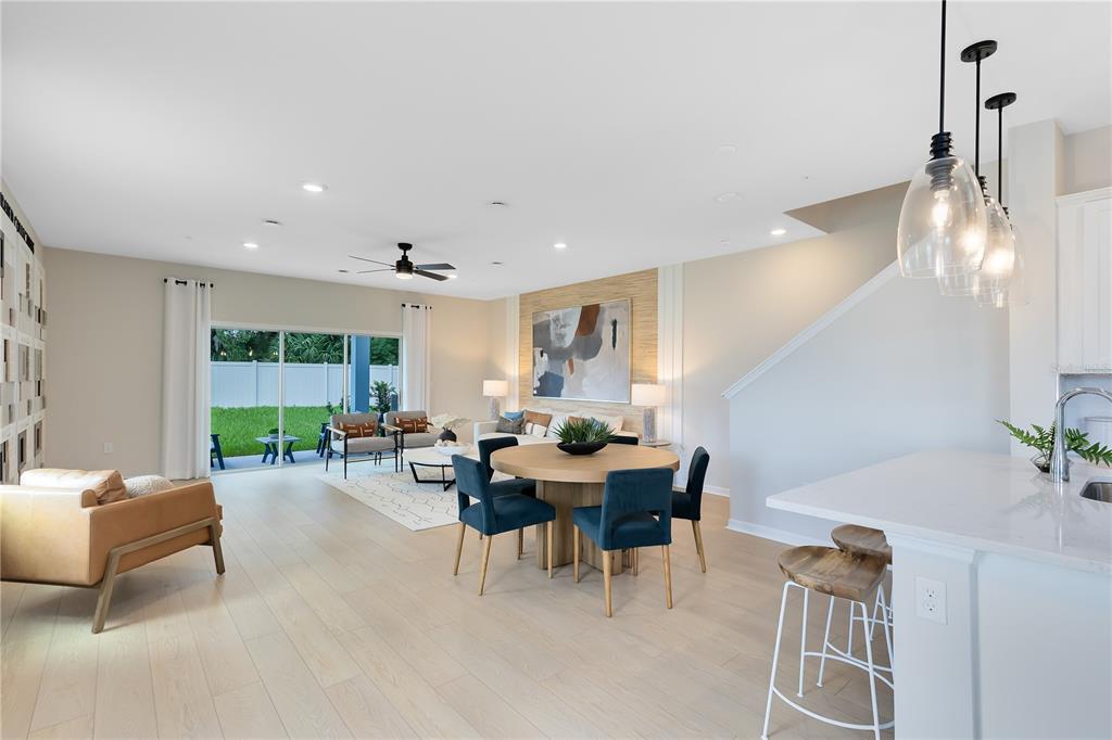 An open-concept living and dining area features light wood floors, a round table, and patio access — 5115 MORNING DEW LANE, WEST MELBOURNE, FL
