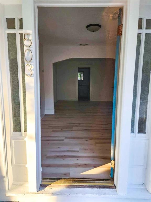 A view through an open doorway into a room with light-colored wood-look flooring — 503 W IDLEWILD AVENUE, TAMPA, FL