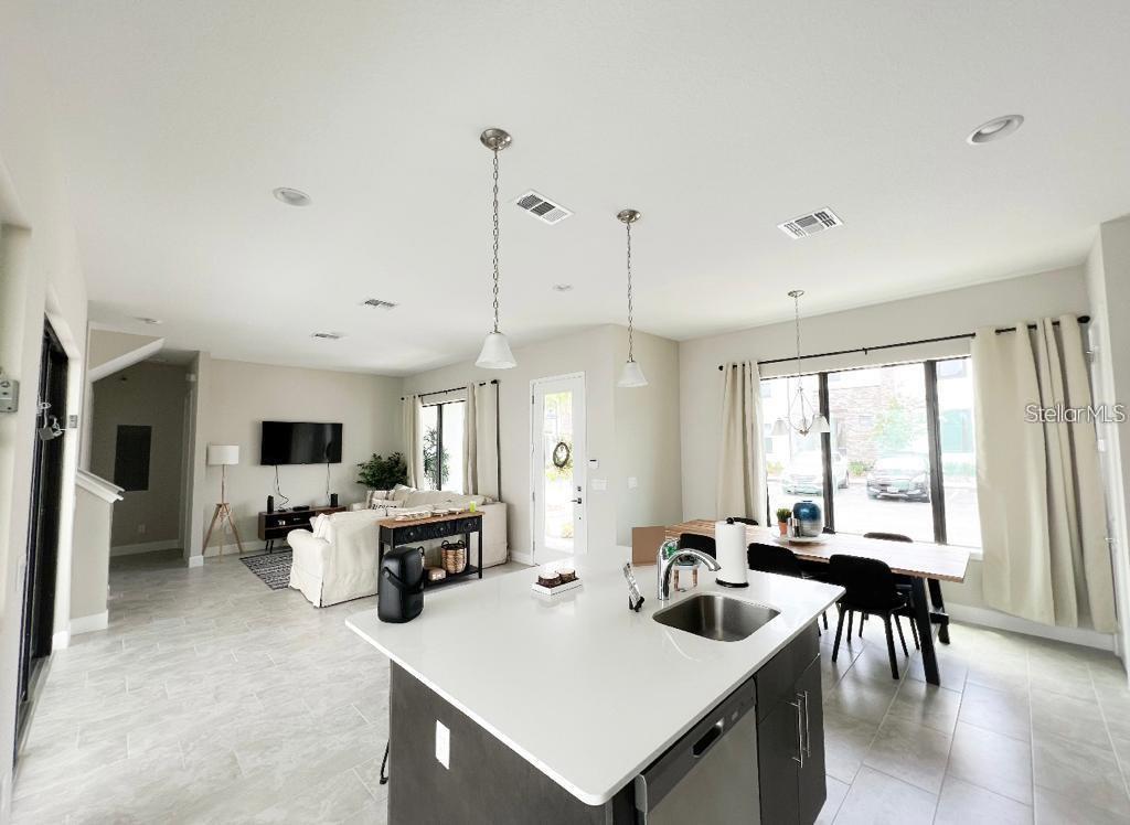 An open-concept kitchen with a white island overlooks a living area and dining space — 175 VILLA DOMANI CIRCLE, DAVENPORT, FL