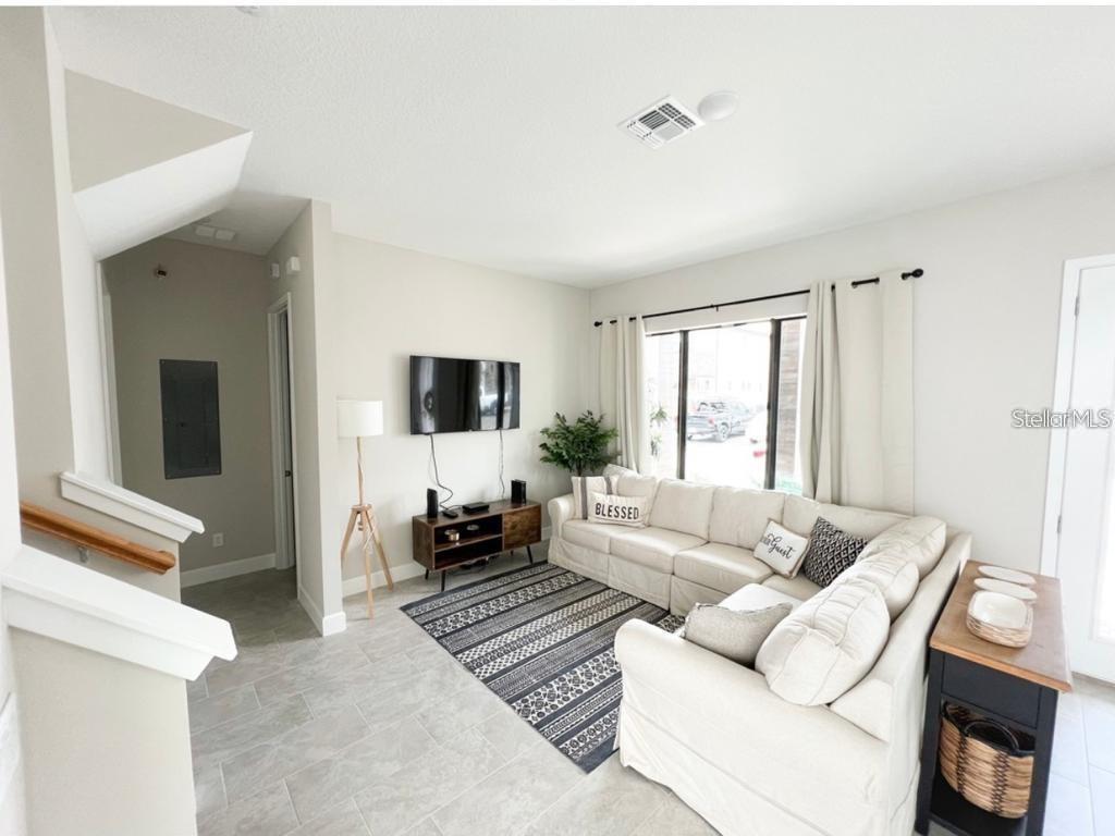 A living room features a white sectional sofa, a patterned area rug, and a wall-mounted television — 175 VILLA DOMANI CIRCLE, DAVENPORT, FL