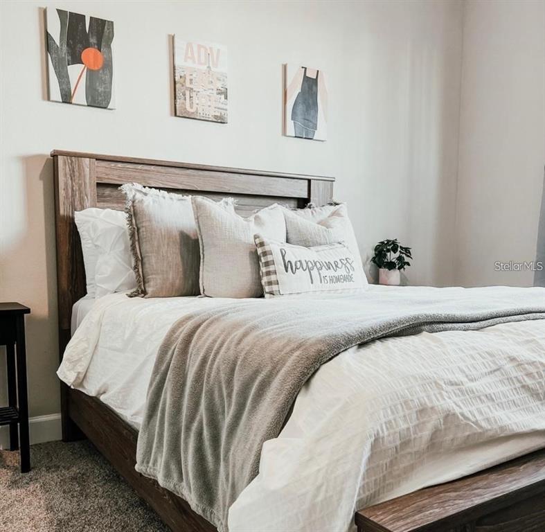 A bedroom features a wooden bed frame, white bedding, and three framed pictures on the wall — 175 VILLA DOMANI CIRCLE, DAVENPORT, FL
