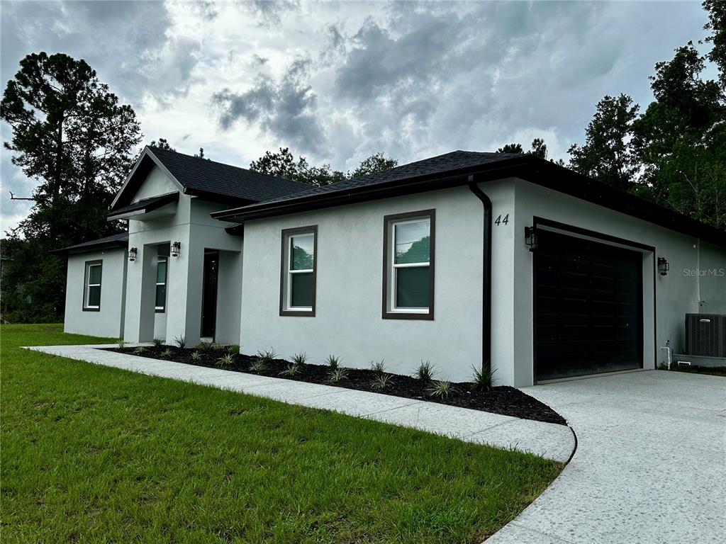 A modern, single-story house with white stucco walls, dark trim, and a one-car garage — 44 KEEBLE AVENUE, DEBARY, FL