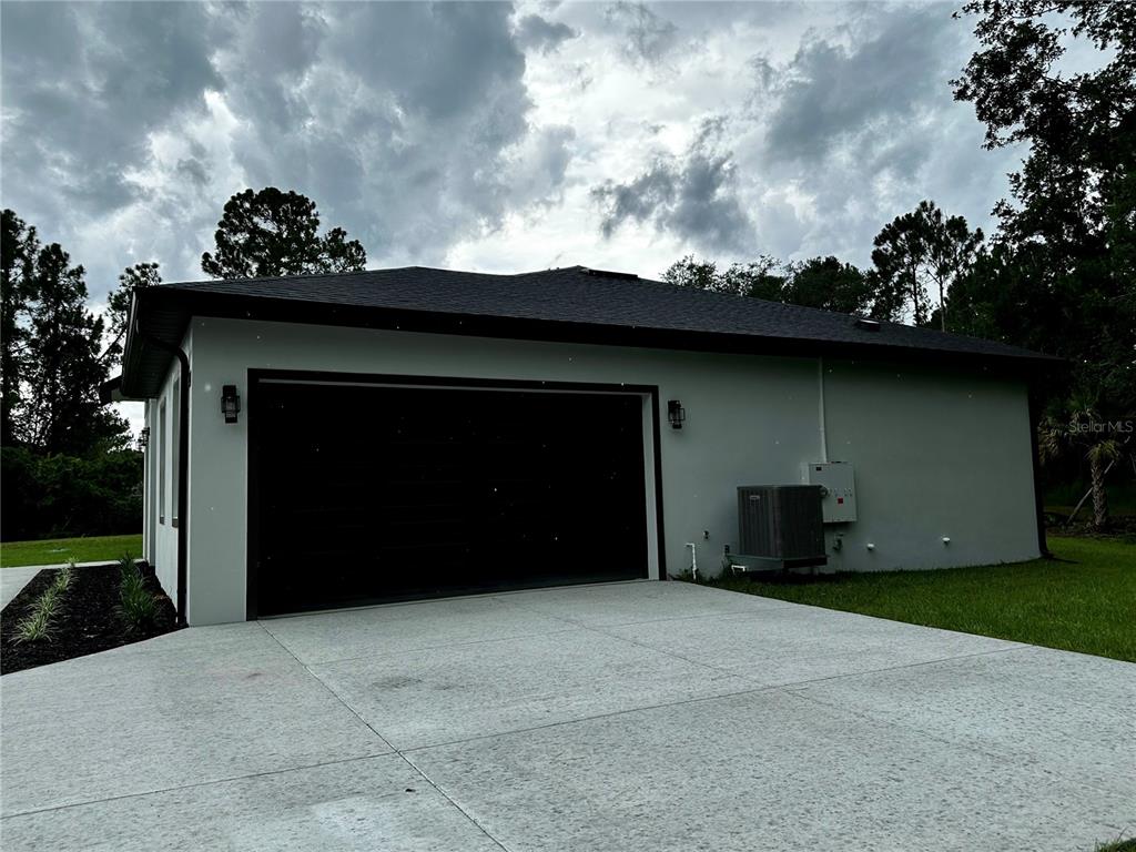 The exterior of a house features a two-car garage, concrete driveway, and an HVAC unit — 44 KEEBLE AVENUE, DEBARY, FL