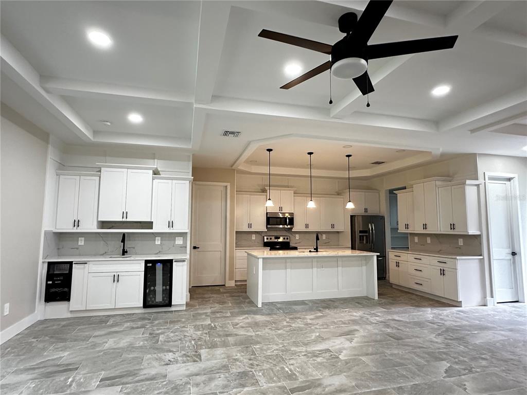 A modern kitchen features white cabinetry, a central island, stainless steel appliances, and tile flooring — 44 KEEBLE AVENUE, DEBARY, FL