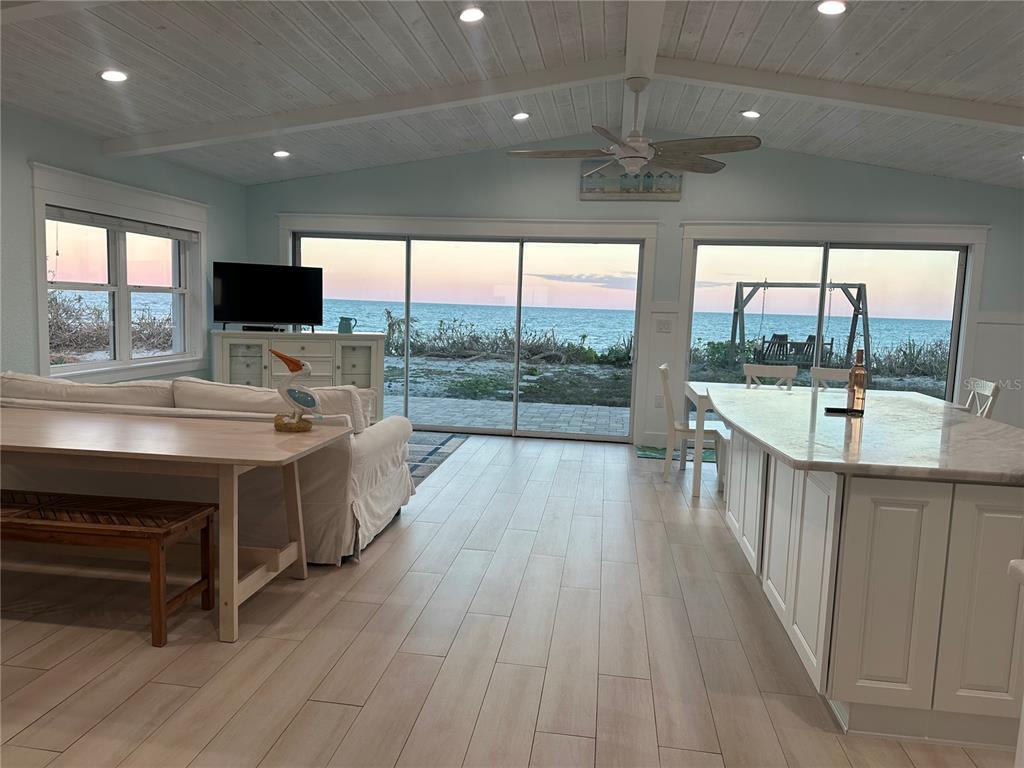 An open-concept living and kitchen area features light wood-look tile floors and panoramic ocean views — 5 PARK AVENUE, SATELLITE BEACH, FL
