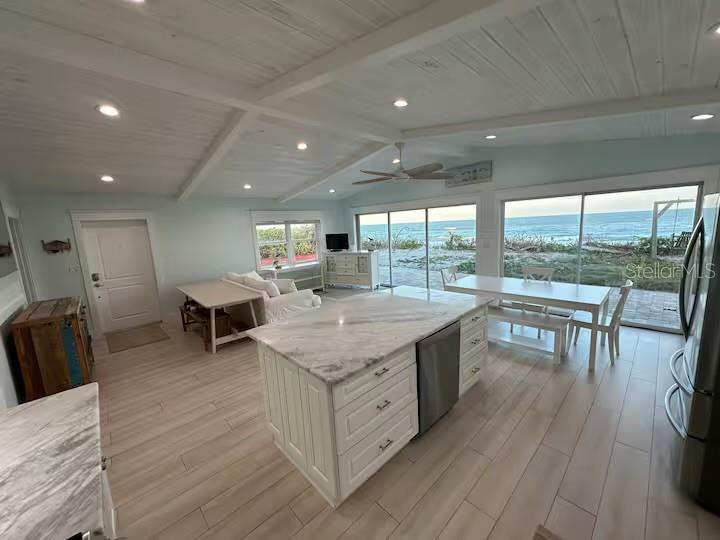 An open-concept kitchen and dining area features a marble island, white cabinetry, and ocean views — 5 PARK AVENUE, SATELLITE BEACH, FL