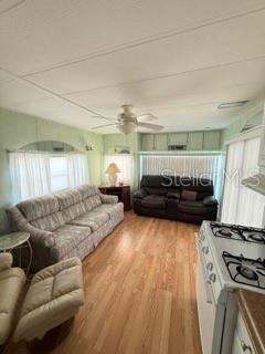 A living room features a sofa, a recliner, a dark loveseat, and light wood flooring — 1475 FLAMINGO DRIVE UNIT 142, ENGLEWOOD, FL
