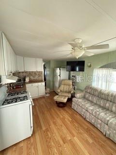 An open-concept kitchen and living area features white cabinets, wood flooring, and a ceiling fan — 1475 FLAMINGO DRIVE UNIT 142, ENGLEWOOD, FL
