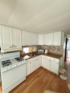 A kitchen features white cabinets, a white stove, and light wood flooring — 1475 FLAMINGO DRIVE UNIT 142, ENGLEWOOD, FL