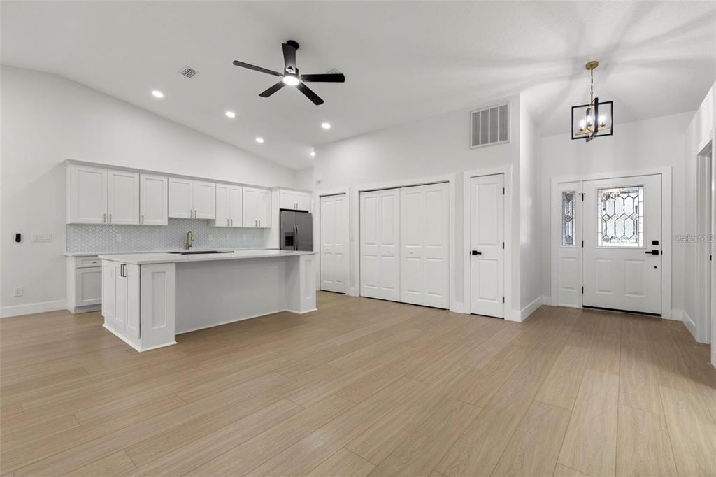 A modern kitchen with white cabinetry, a large island, and light wood flooring — 6549 BRENTWOOD DRIVE, ZEPHYRHILLS, FL