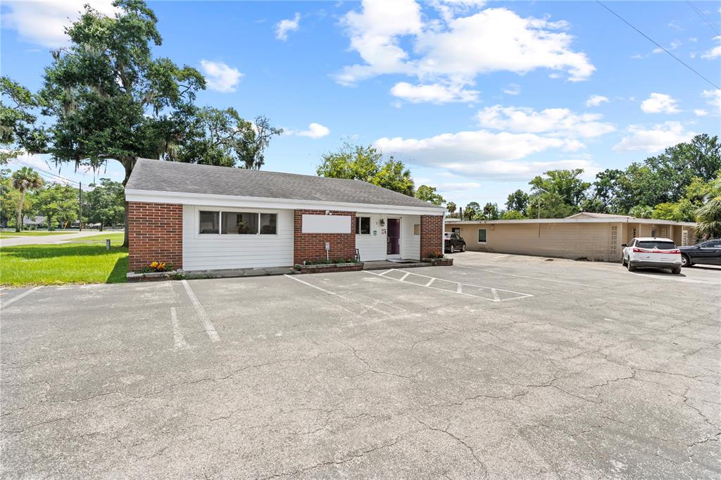 A single-story brick and white siding commercial building with an attached parking lot — 117 NE 1ST STREET, CHIEFLAND, FL