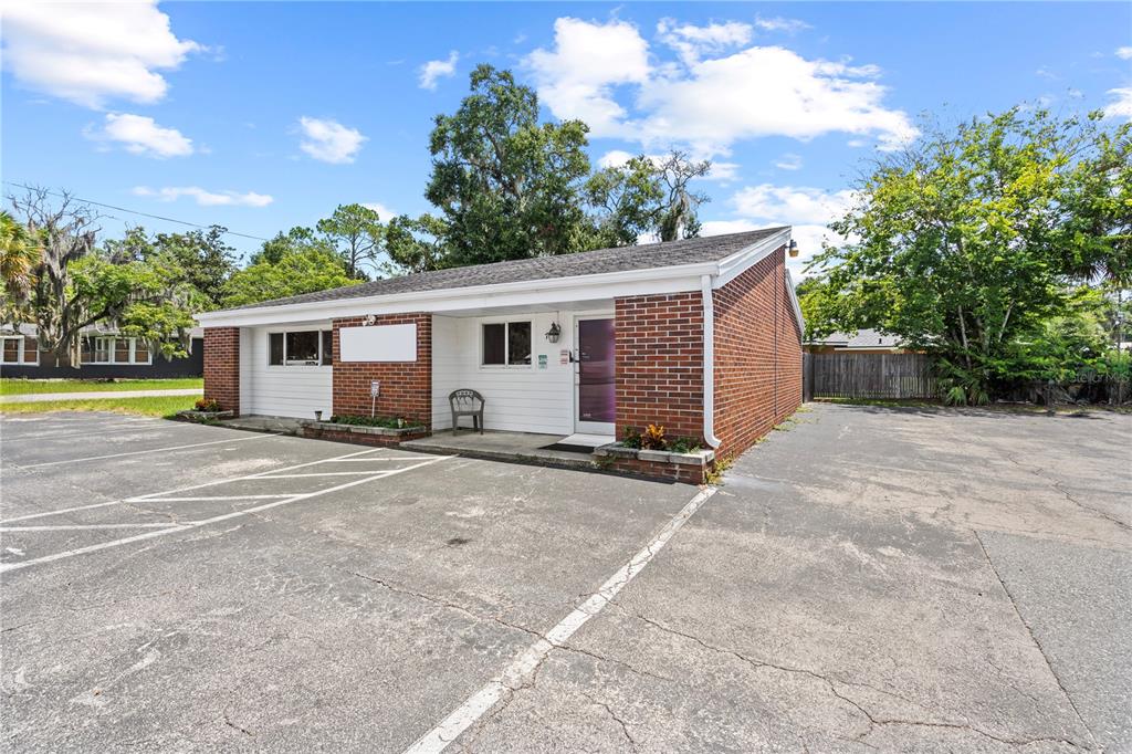 A single-story brick and white siding commercial building with a paved parking lot — 117 NE 1ST STREET, CHIEFLAND, FL