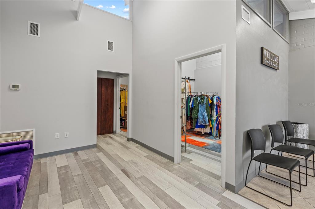 A room with light wood-look flooring, gray walls, a purple sofa, and two doorways leading to closets — 117 NE 1ST STREET, CHIEFLAND, FL