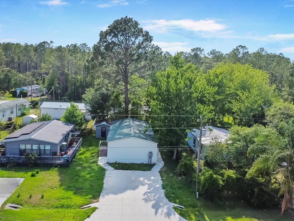 An aerial view shows a white house with a driveway, surrounded by trees and neighboring homes — 54735 WILLIAMS STREET, ASTOR, FL