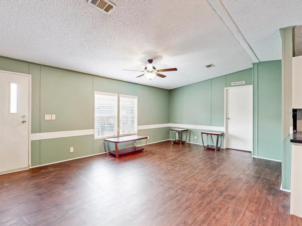 A living room with sage green walls, wood-look flooring, and a ceiling fan — 54735 WILLIAMS STREET, ASTOR, FL