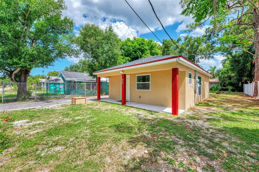 A small, tan, single-story house with a red-trimmed roof and red support columns — 1420 19TH AVENUE W, BRADENTON, FL