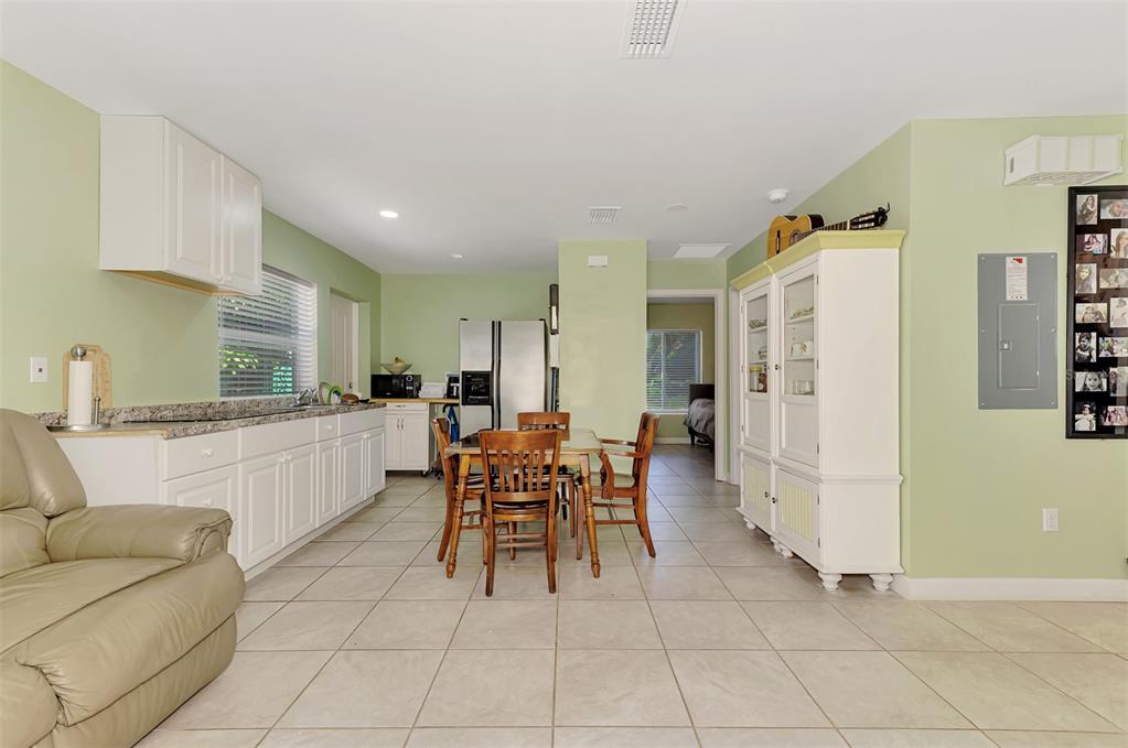 A kitchen with white cabinets, granite countertops, and a dining table sits on tiled floors — 1420 19TH AVENUE W, BRADENTON, FL