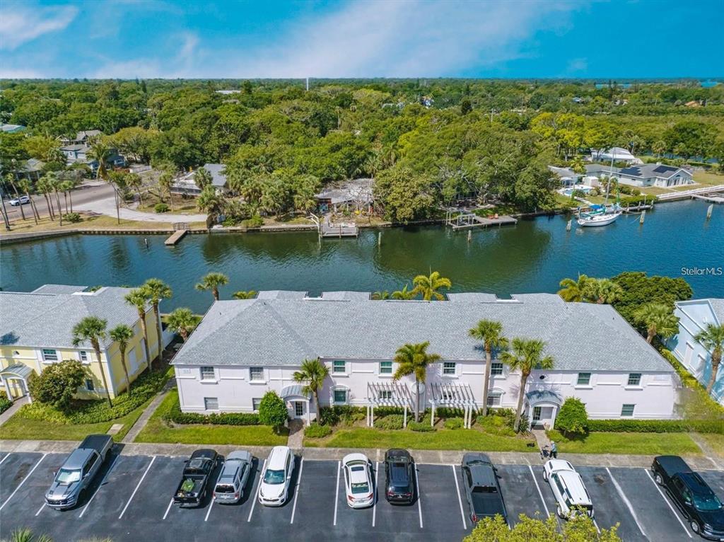 An aerial view of a multi-story residential building with a parking lot and waterfront canal — 3873 POMPANO DRIVE SE UNIT D, ST PETERSBURG, FL