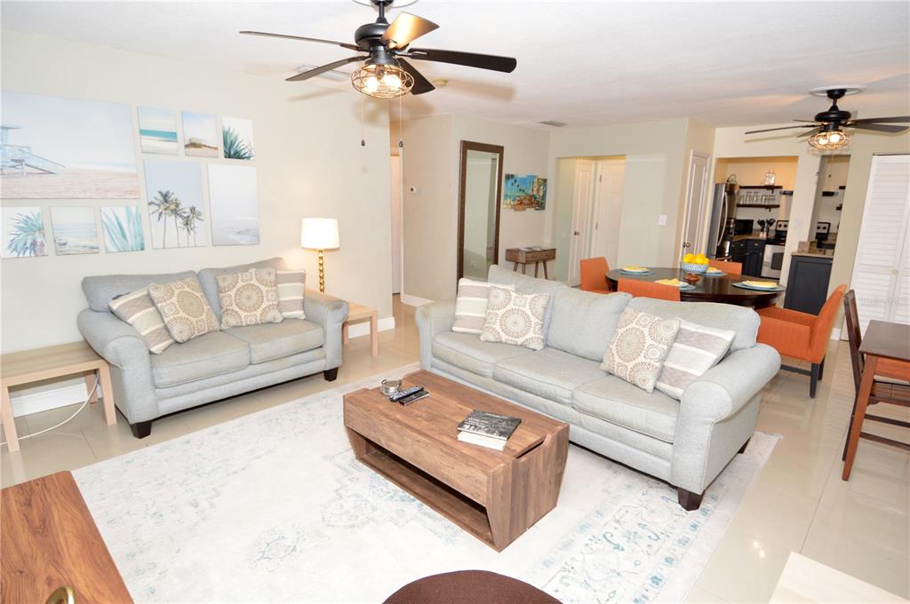 A living room features two light gray sofas, a wooden coffee table, and a dining area — 3873 POMPANO DRIVE SE UNIT D, ST PETERSBURG, FL