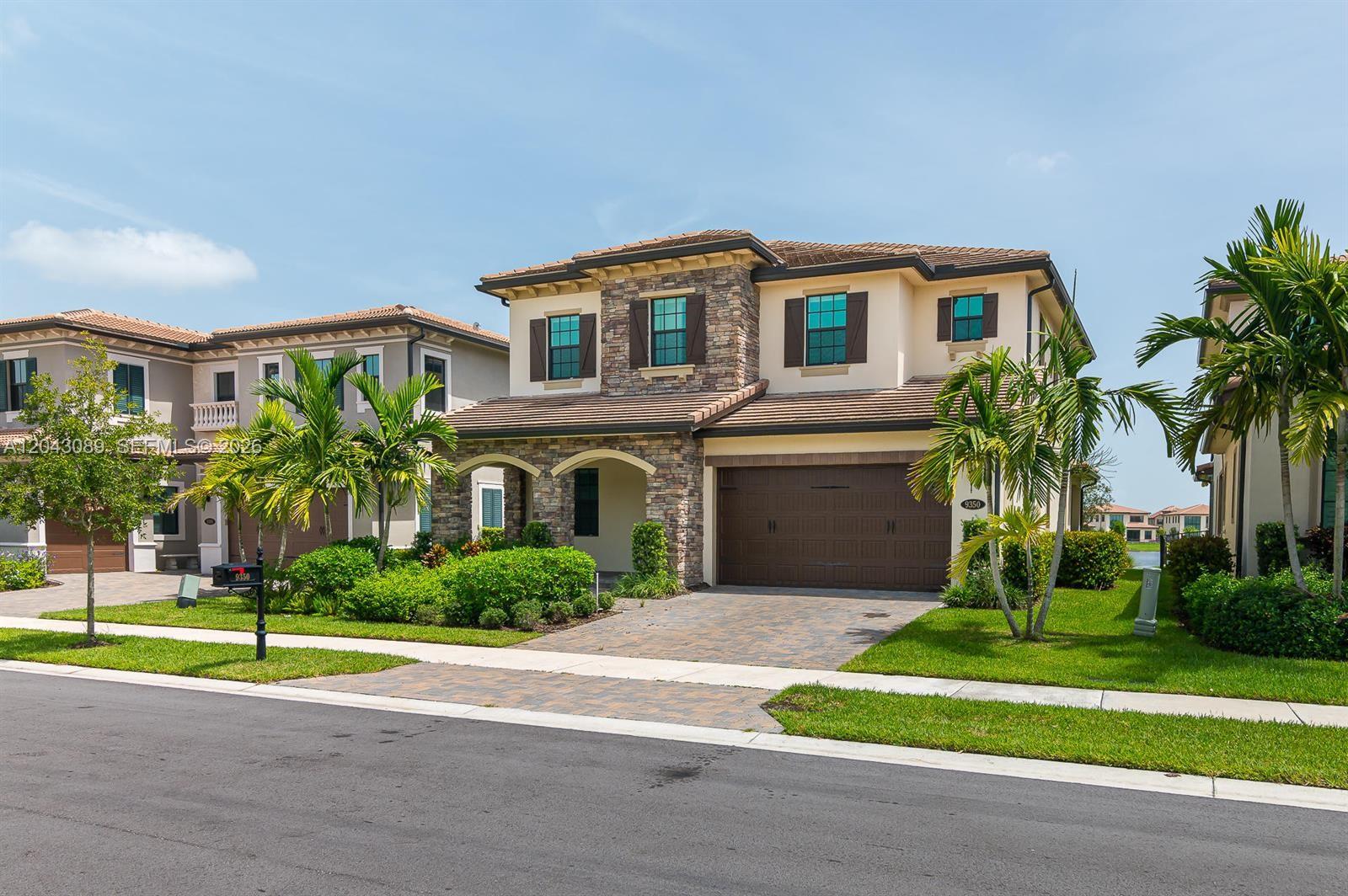 A two-story suburban house with a stone facade, brown garage door, and palm trees — 9350 Solstice Cir, Parkland FL 33076, PARKLAND, FL